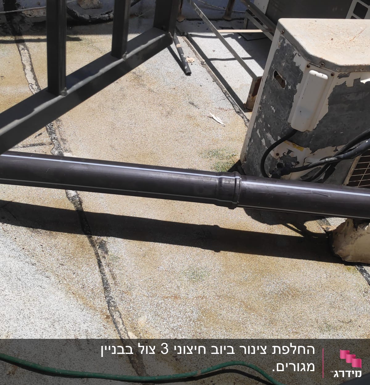 צינור פלסטיק שחור על גג עם מזגן ישן